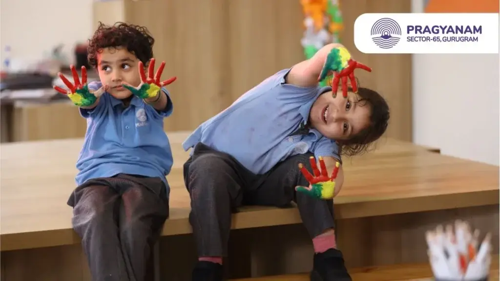 Two children with painted hands sitting on a table